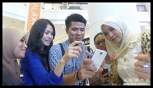Awal Ashaari and Liyana Jasmay showing or demonstrating the cool features of the Samsung Galaxy S4 to interested buyers.