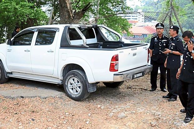 Where’s the boy?: ACP Jauteh (left) and his police officers at the scene where the stolen vehicle was found near Signal Hill in Kota Kinabalu.