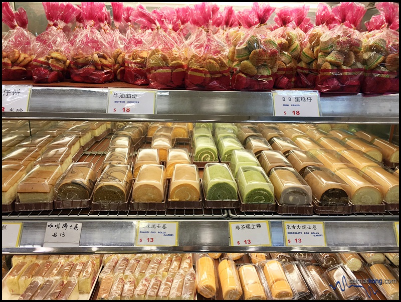 The shelves are loaded with a variety of cakes, rolls, sandwich, breads and pastries.